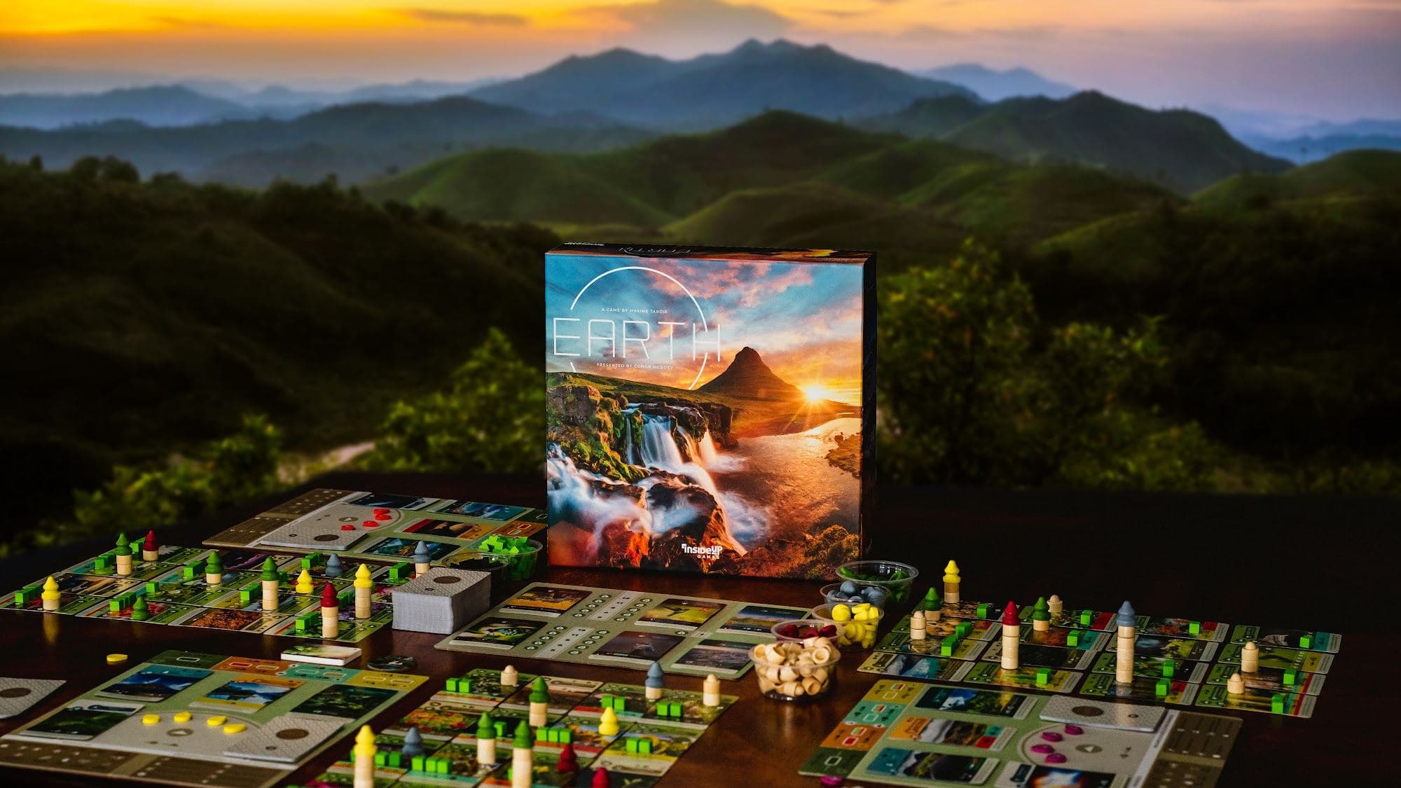 The Earth box on a game table with a mountain sunset behind it